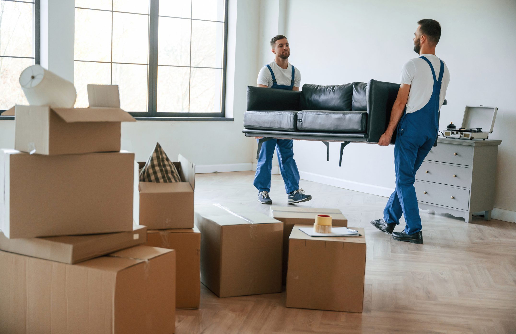 Movers carrying couch in a room.