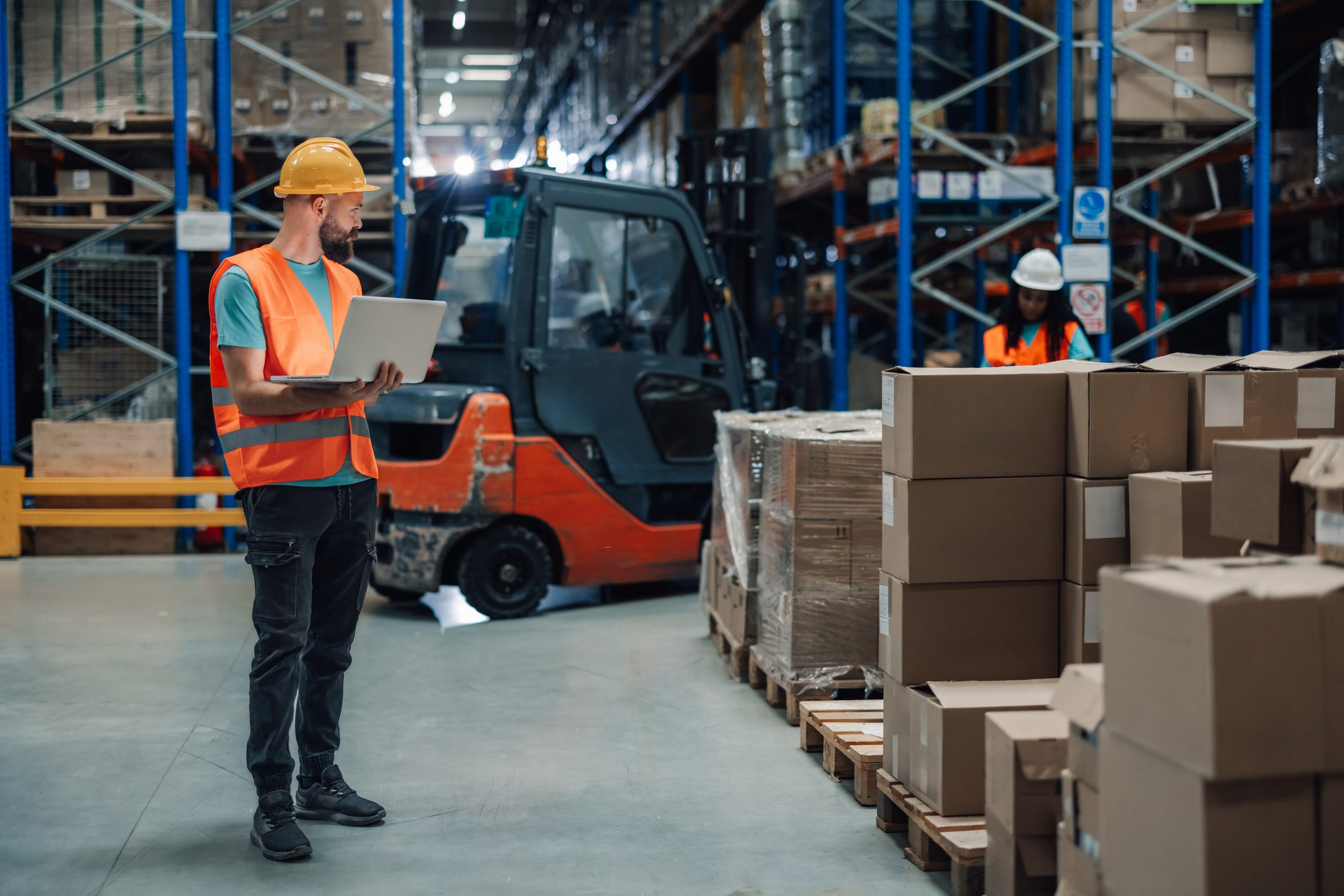 Warehouse workers with forklift and boxes.