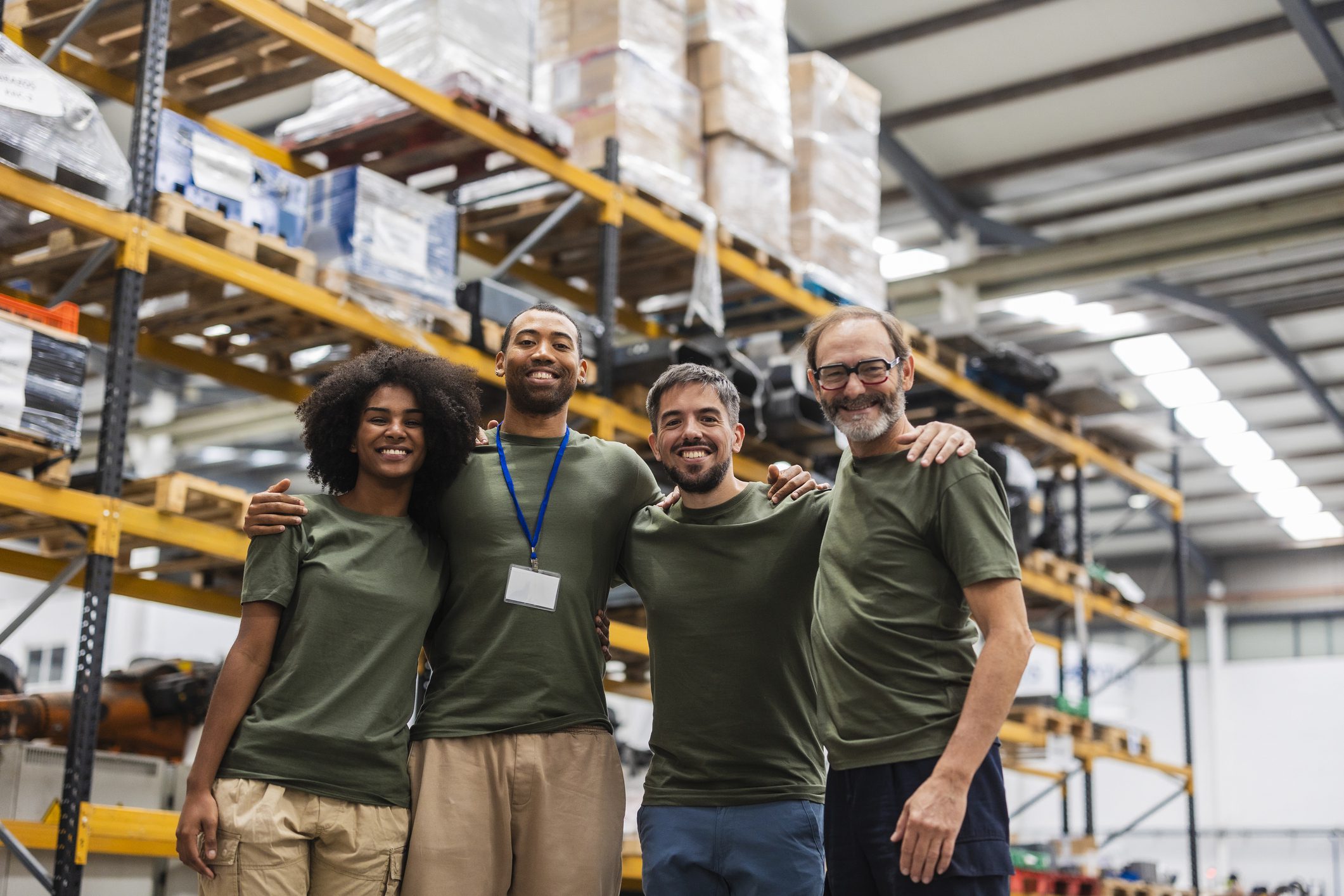Warehouse team smiling in front of shelves.