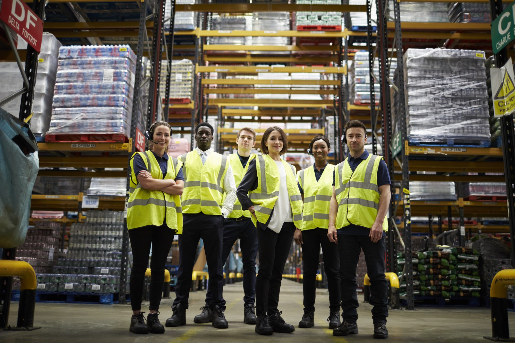 Warehouse team wearing safety vests, standing together.